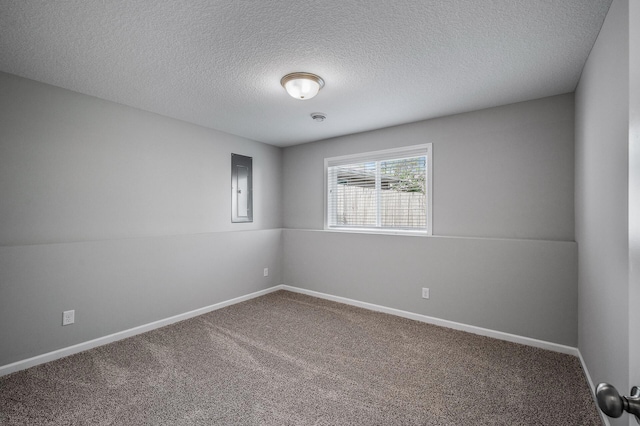 carpeted spare room with a textured ceiling, baseboards, and electric panel