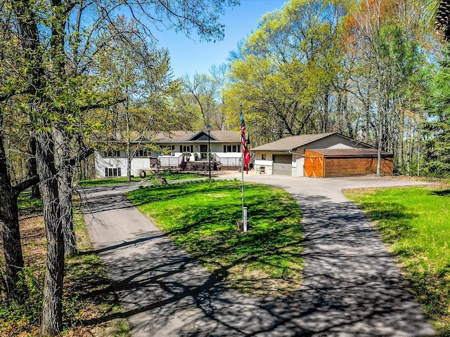 ranch-style home with asphalt driveway, a front lawn, brick siding, a detached garage, and a porch