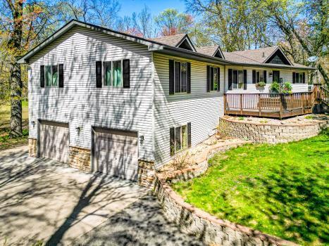 view of front facade with an attached garage, concrete driveway, a wooden deck, and a front lawn