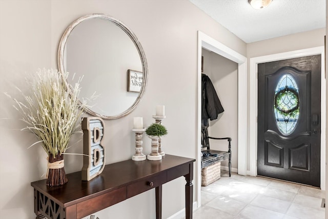entrance foyer featuring light tile patterned flooring, a textured ceiling, and baseboards