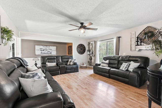 living area with a textured ceiling, ceiling fan, and wood finished floors