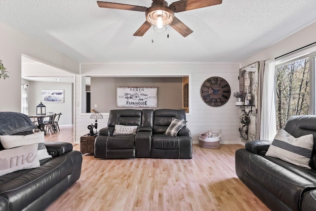 living area with wood finished floors, a textured ceiling, a ceiling fan, and baseboards