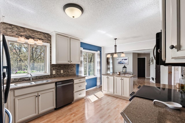 kitchen featuring black appliances, a sink, a textured ceiling, light wood finished floors, and tasteful backsplash
