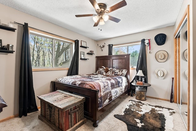 carpeted bedroom featuring a textured ceiling, baseboards, and ceiling fan