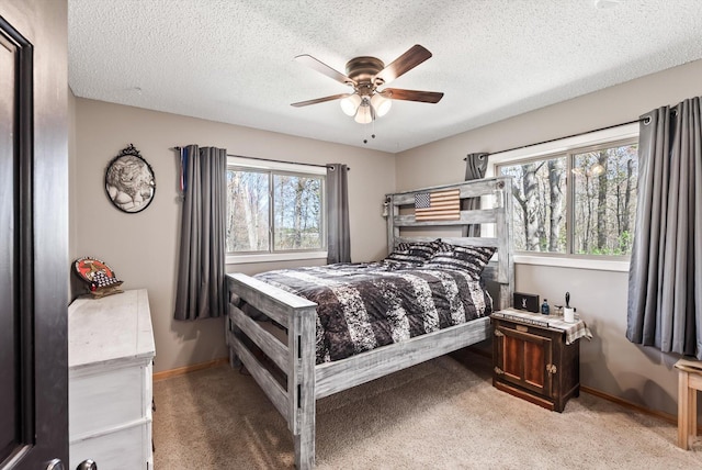 bedroom with light colored carpet, baseboards, a textured ceiling, and ceiling fan