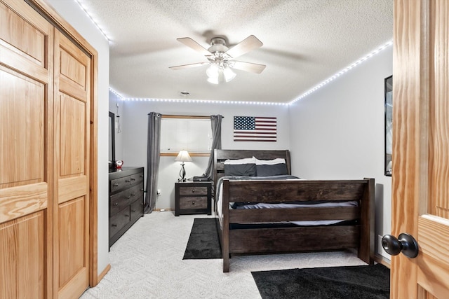bedroom with light carpet, ceiling fan, and a textured ceiling