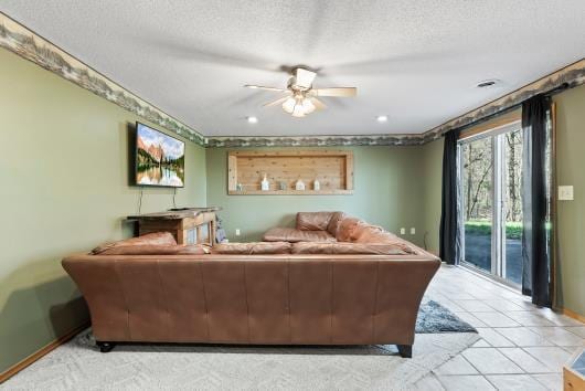 living room featuring ceiling fan, a textured ceiling, light tile patterned floors, and baseboards