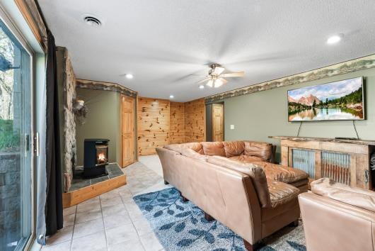 living room featuring a ceiling fan, recessed lighting, a wood stove, and light tile patterned floors