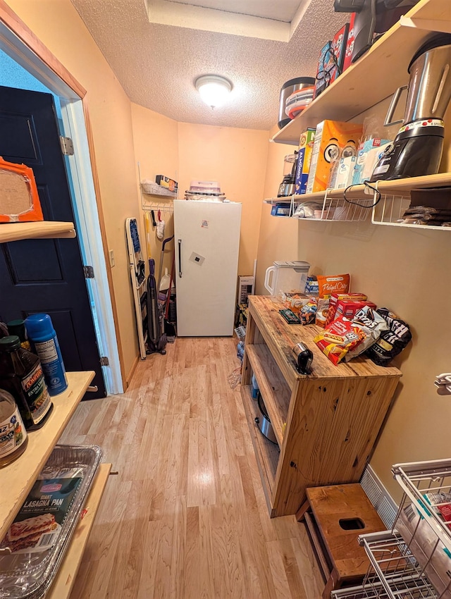 laundry area with light wood-style floors and a textured ceiling