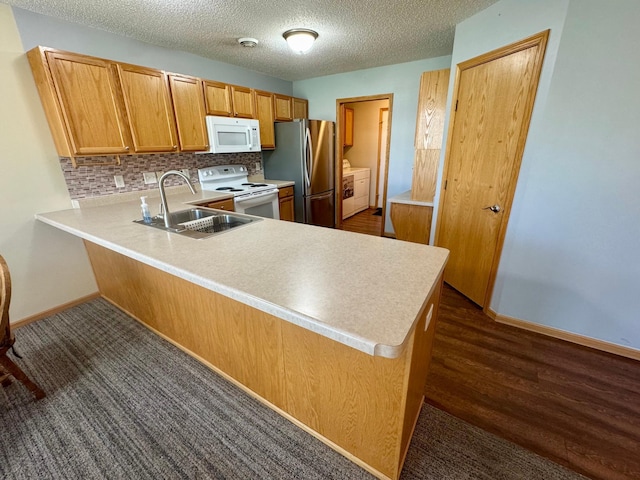 kitchen featuring white appliances, a sink, a peninsula, decorative backsplash, and light countertops