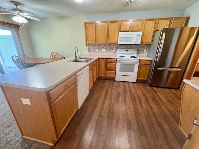 kitchen featuring white appliances, a sink, dark wood-style floors, light countertops, and decorative backsplash