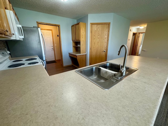 kitchen with white appliances, a sink, dark wood-style floors, a textured ceiling, and brown cabinets