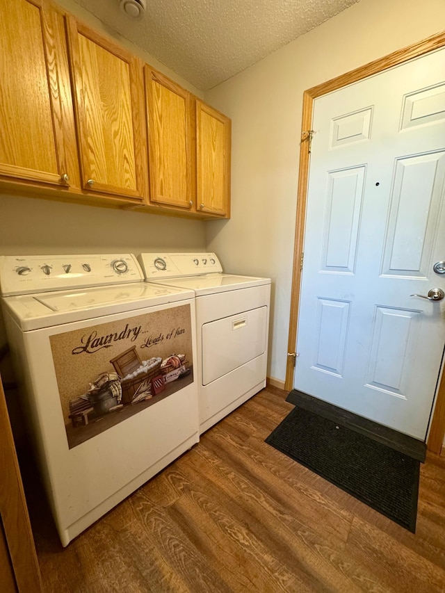 washroom featuring washing machine and clothes dryer, cabinet space, dark wood finished floors, and a textured ceiling