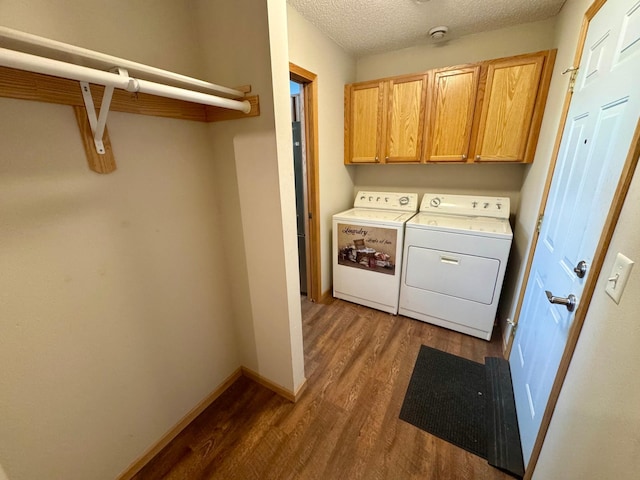 laundry area with washing machine and clothes dryer, dark wood-type flooring, cabinet space, a textured ceiling, and baseboards