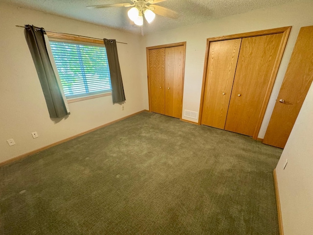 unfurnished bedroom with two closets, carpet floors, a textured ceiling, a ceiling fan, and baseboards