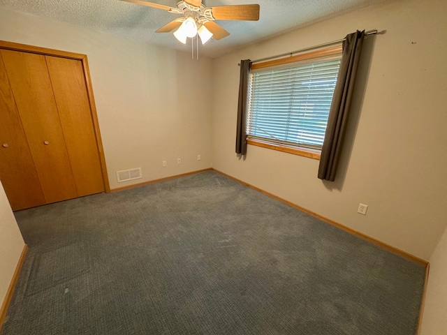 unfurnished bedroom featuring a textured ceiling, baseboards, carpet floors, ceiling fan, and a closet