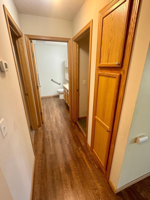 hallway featuring dark wood-style floors and a textured ceiling