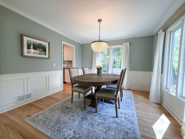 14700 Minnehaha Pl, Minnetonka, MN 55391 - dining space featuring a chandelier, plenty of natural light, light wood-style floors, ornamental molding, and a decorative wall
