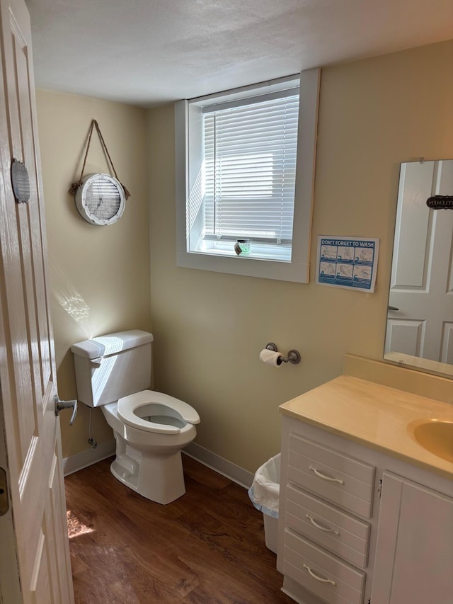 211 1st Ave, Osakis, MN 56360 - bathroom featuring baseboards, wood finished floors, toilet, and vanity
