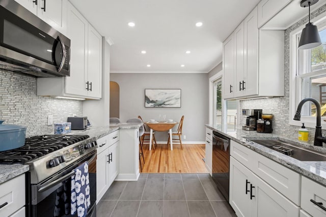kitchen featuring appliances with stainless steel finishes, a sink, tile patterned flooring, decorative backsplash, and white cabinetry