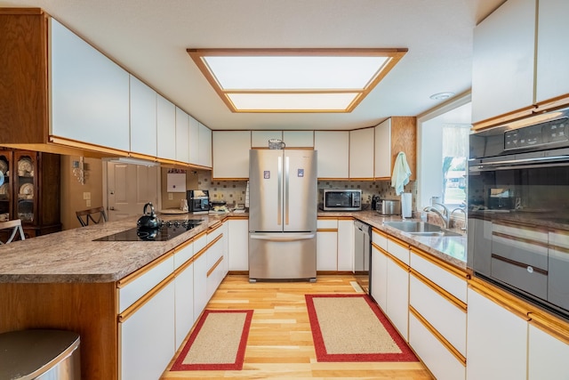 402 2nd Ave SE, Mapleton, MN 56065 - kitchen with appliances with stainless steel finishes, a sink, light wood-style floors, tasteful backsplash, and white cabinets
