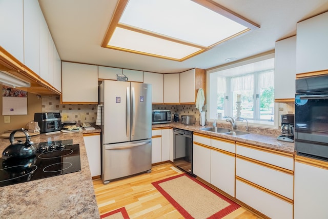 402 2nd Ave SE, Mapleton, MN 56065 - kitchen featuring black appliances, a sink, light wood-type flooring, decorative backsplash, and light countertops