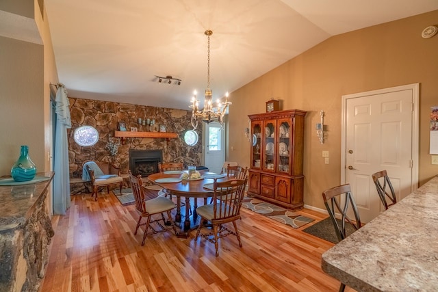 402 2nd Ave SE, Mapleton, MN 56065 - dining area featuring light wood-style floors, a fireplace, vaulted ceiling, and a chandelier