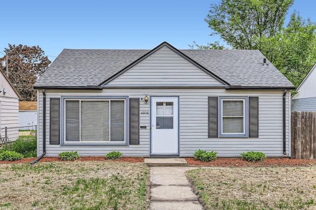bungalow featuring roof with shingles and fence