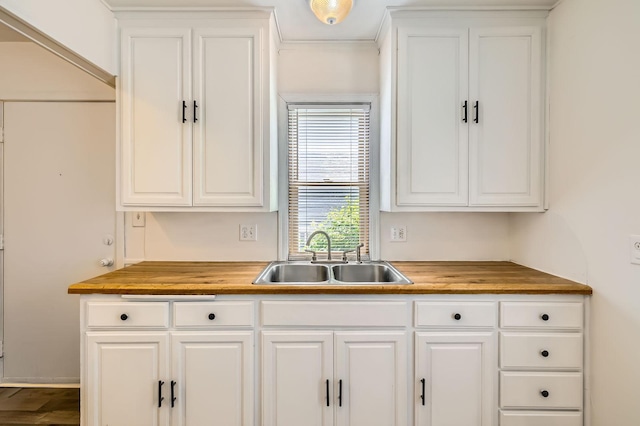 kitchen with a sink, butcher block countertops, and white cabinetry