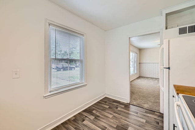 unfurnished dining area featuring dark wood finished floors and baseboards