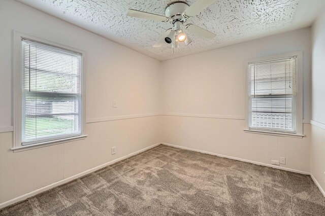 spare room with carpet flooring, ceiling fan, a textured ceiling, and baseboards
