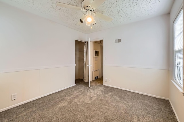 carpeted empty room with ceiling fan and baseboards