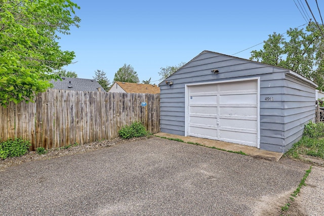 detached garage featuring fence and asphalt driveway