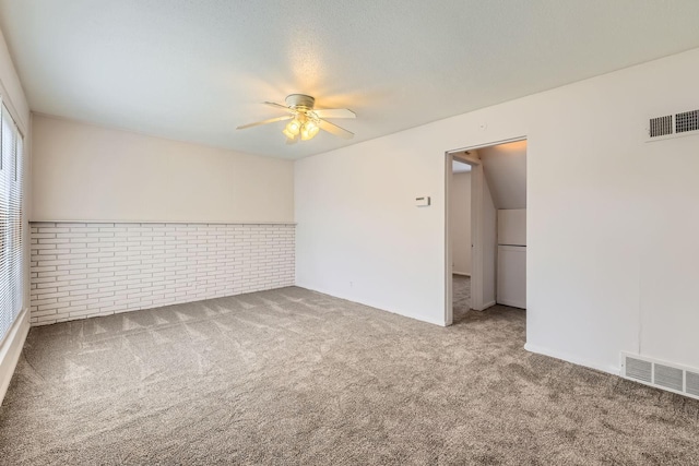 empty room featuring carpet, ceiling fan, and brick wall