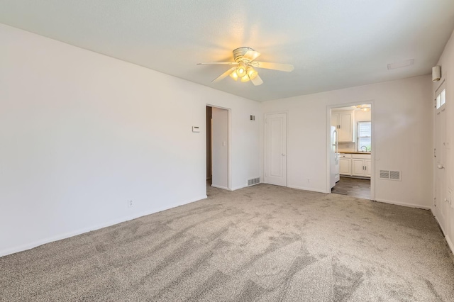 unfurnished bedroom featuring carpet, ensuite bathroom, baseboards, a ceiling fan, and a sink