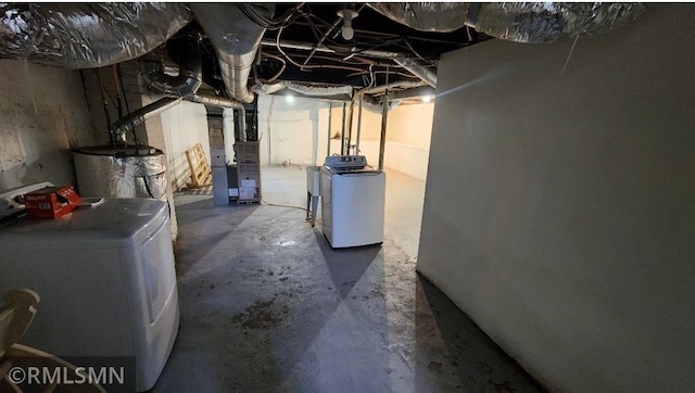 unfinished basement featuring separate washer and dryer and heating unit