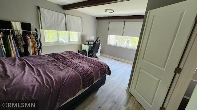 bedroom with beamed ceiling, wood finished floors, and baseboards