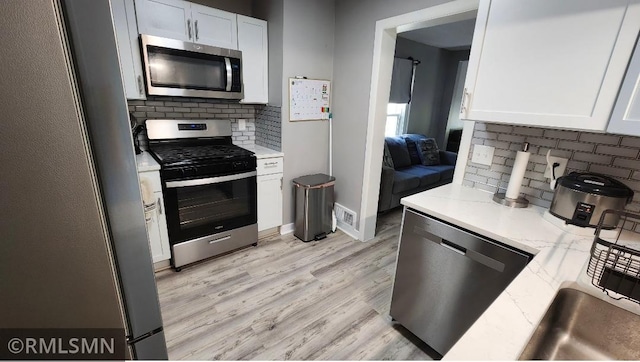 kitchen with appliances with stainless steel finishes, backsplash, and white cabinets