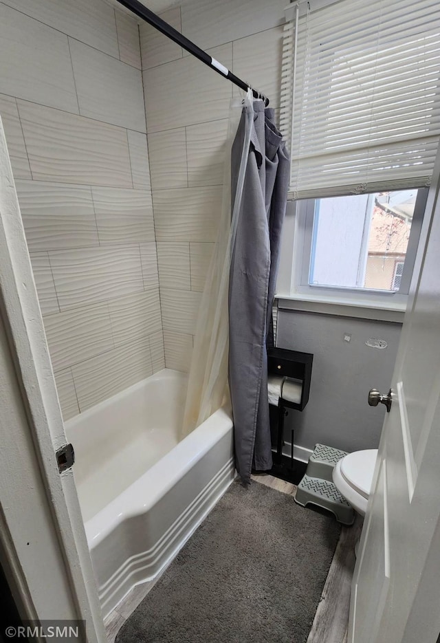 bathroom featuring toilet, shower / bath combo with shower curtain, wood finished floors, and baseboards