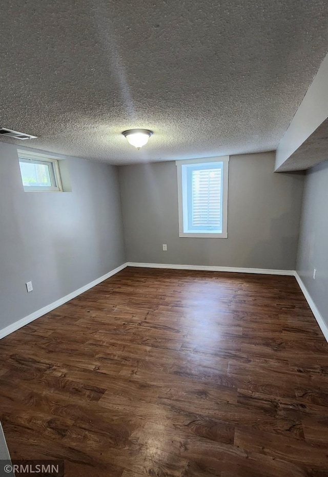 below grade area featuring dark wood finished floors, baseboards, and a textured ceiling