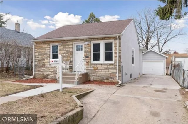 bungalow-style house with stone siding, a garage, an outbuilding, concrete driveway, and fence