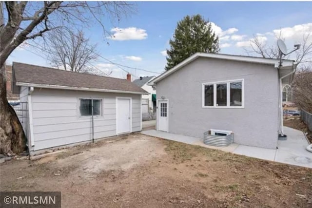 rear view of house featuring stucco siding and an outbuilding