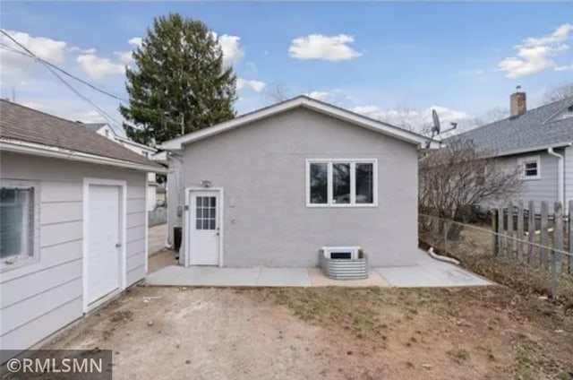rear view of house featuring fence and stucco siding