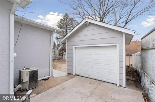 detached garage featuring cooling unit and fence