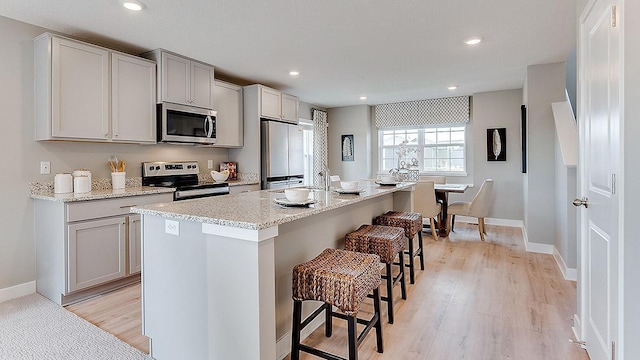 3045 125th Ln NE Unit A, Blaine, MN 55449 - kitchen with stainless steel appliances, a kitchen breakfast bar, a center island with sink, light wood finished floors, and recessed lighting