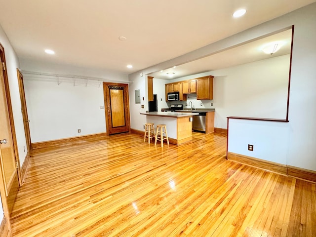 3116 12th Ave S Unit A209, Minneapolis, MN 55407 - kitchen featuring stainless steel appliances, light wood-type flooring, a peninsula, a breakfast bar area, and baseboards
