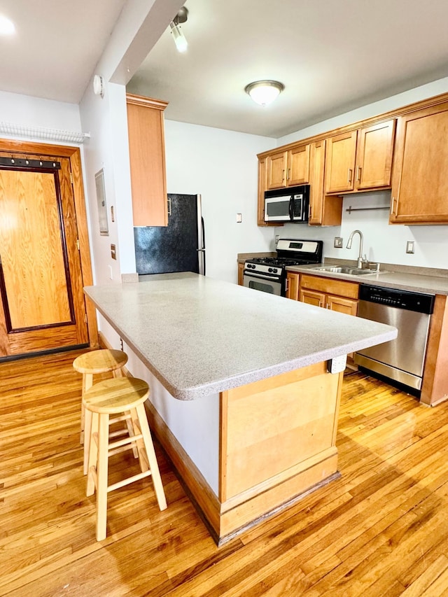 3116 12th Ave S Unit A209, Minneapolis, MN 55407 - kitchen with appliances with stainless steel finishes, light wood-style floors, a peninsula, a breakfast bar area, and a sink