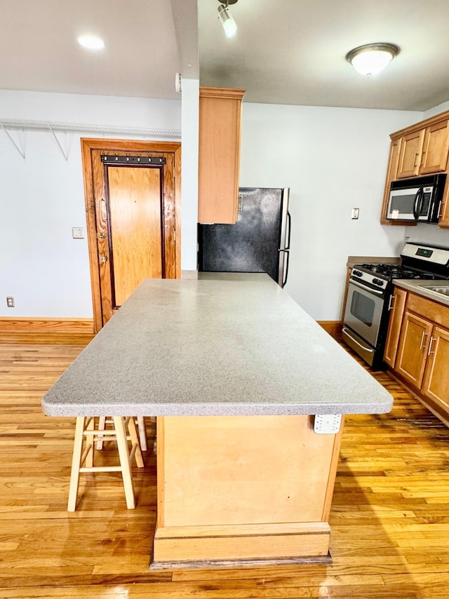3116 12th Ave S Unit A209, Minneapolis, MN 55407 - kitchen featuring appliances with stainless steel finishes, light wood-style floors, a peninsula, and a kitchen breakfast bar