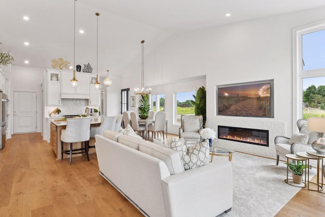 4549 Tovero Trl, Medina, MN 55340 - living room with plenty of natural light, high vaulted ceiling, a glass covered fireplace, light wood-type flooring, and a chandelier