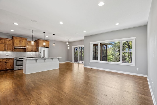 18041 224th Ave NW, Big Lake Twp, MN 55309 - kitchen featuring appliances with stainless steel finishes, brown cabinets, a breakfast bar, baseboards, and recessed lighting